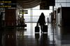 A passenger wheels a suitcase through an airport in Spain.