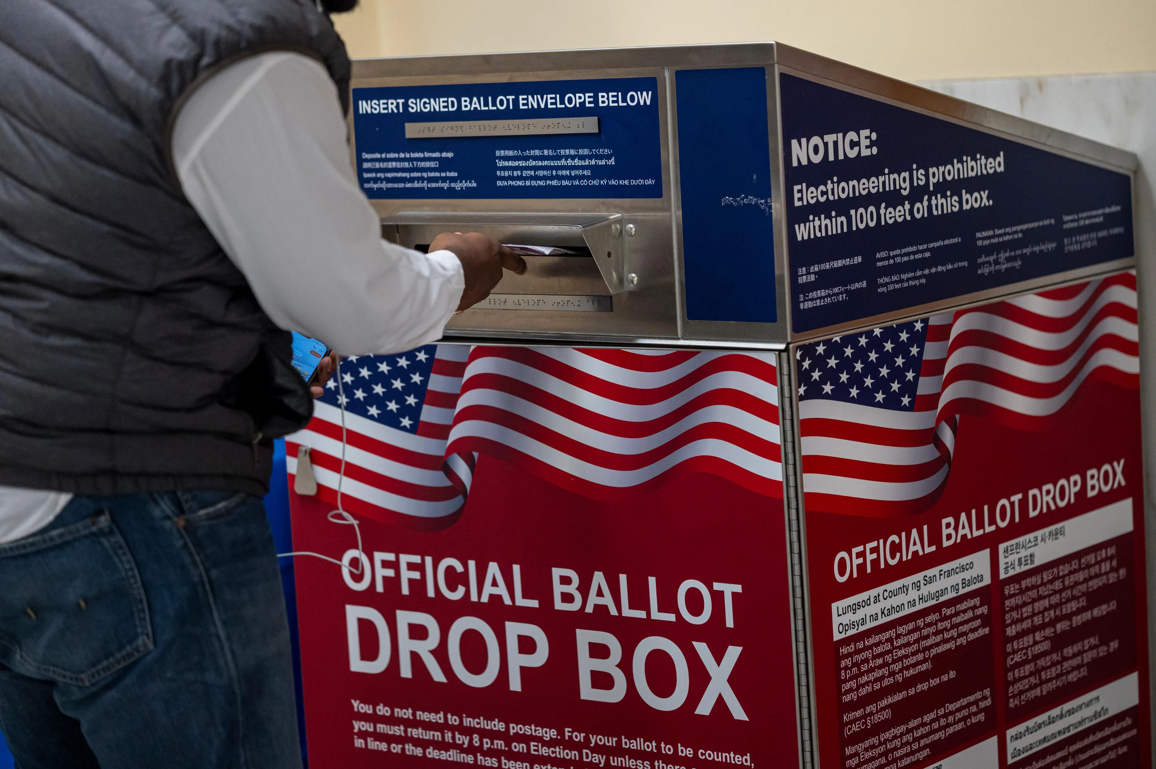 A voter submits their ballot at an official ballot drop box at a polling location in San Francisco.