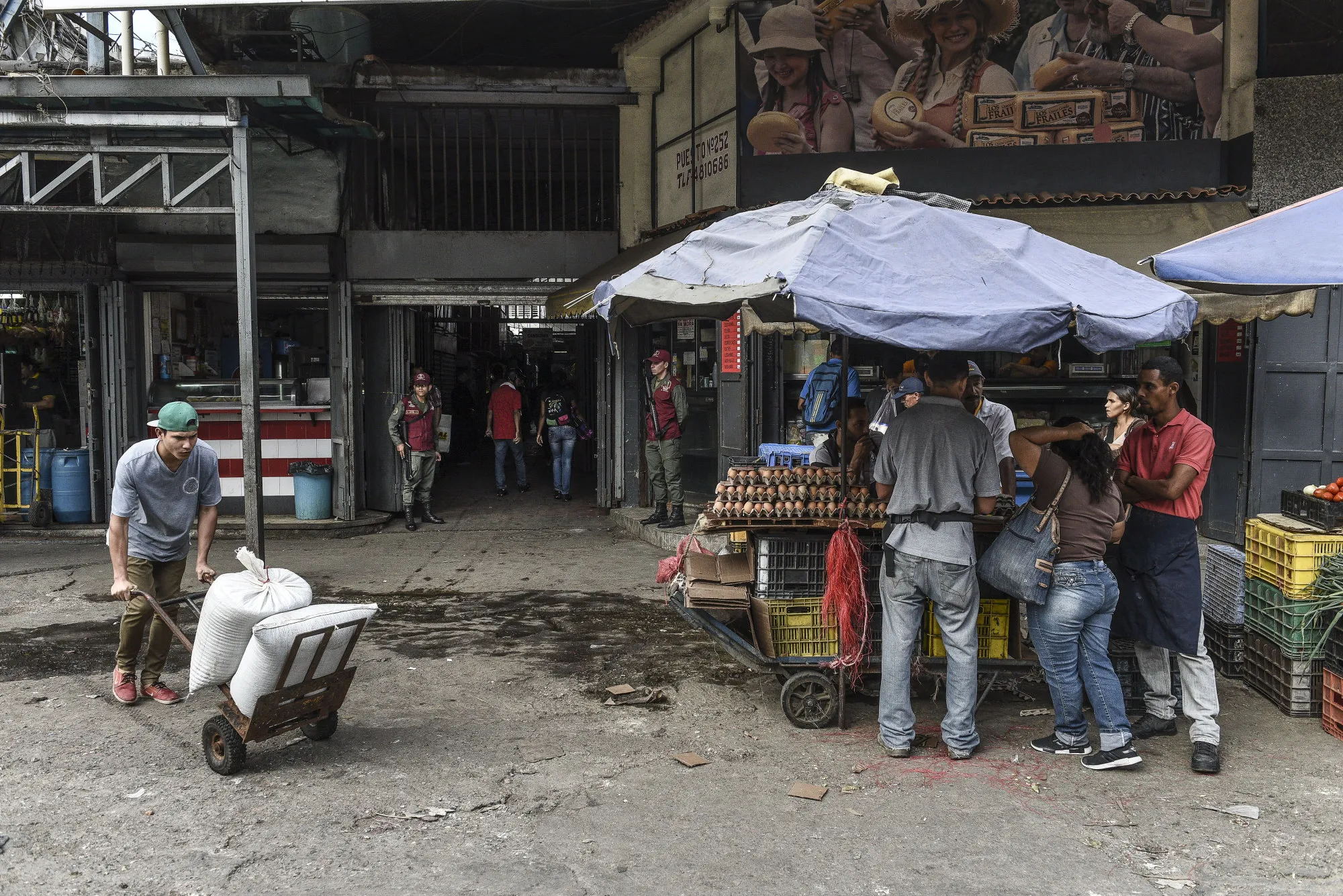 Members of the Bolivarian National Guard stand guard as shoppers browse goods at the Municipal Market of Quinta Crespo in Caracas, on June 20, 2018.