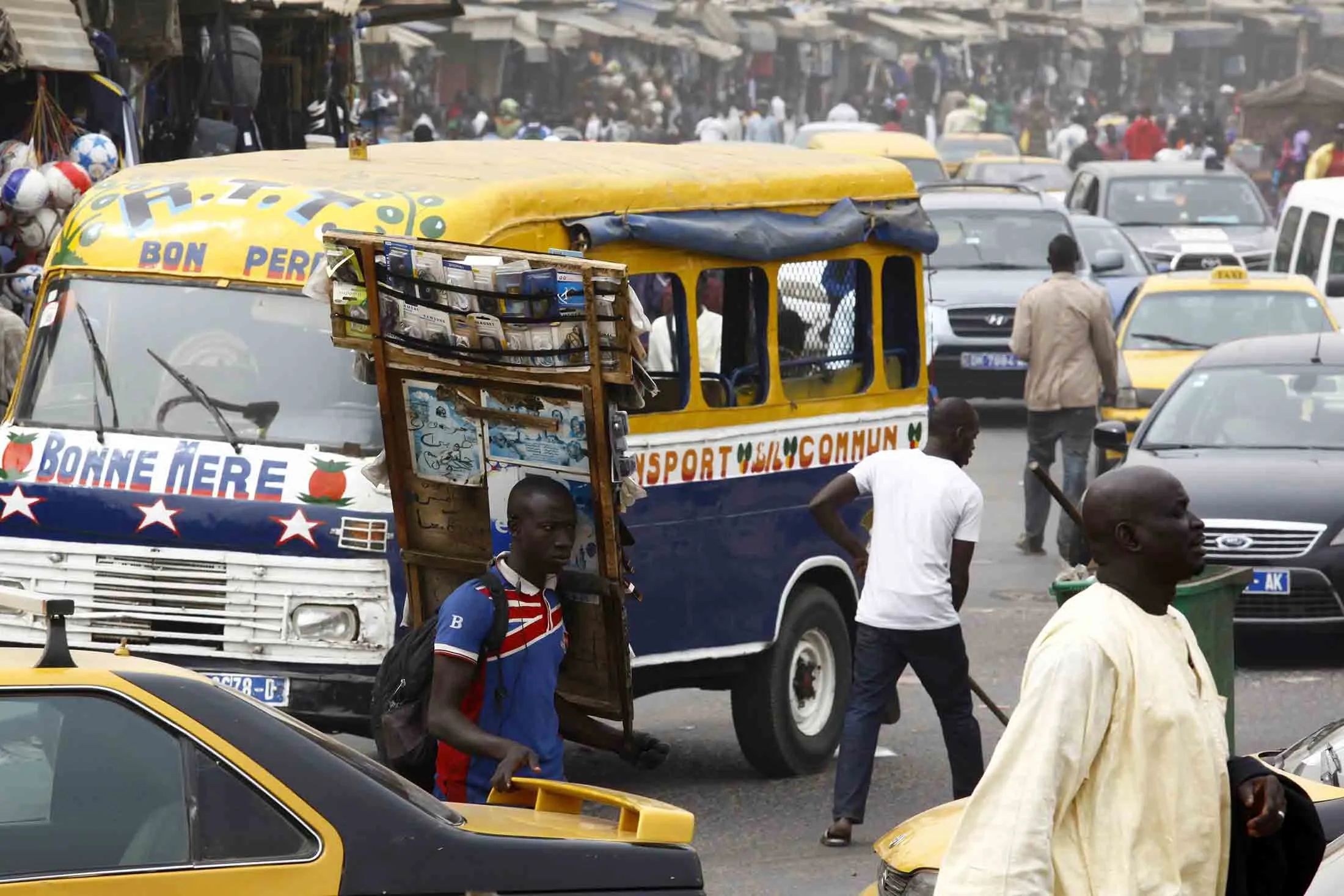 Street traders and road traffic fill a street in Dakar, Senegal.
