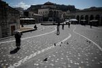 People walk across the empty Monastiraki square under the Acropolis in central Athens, on March 18.