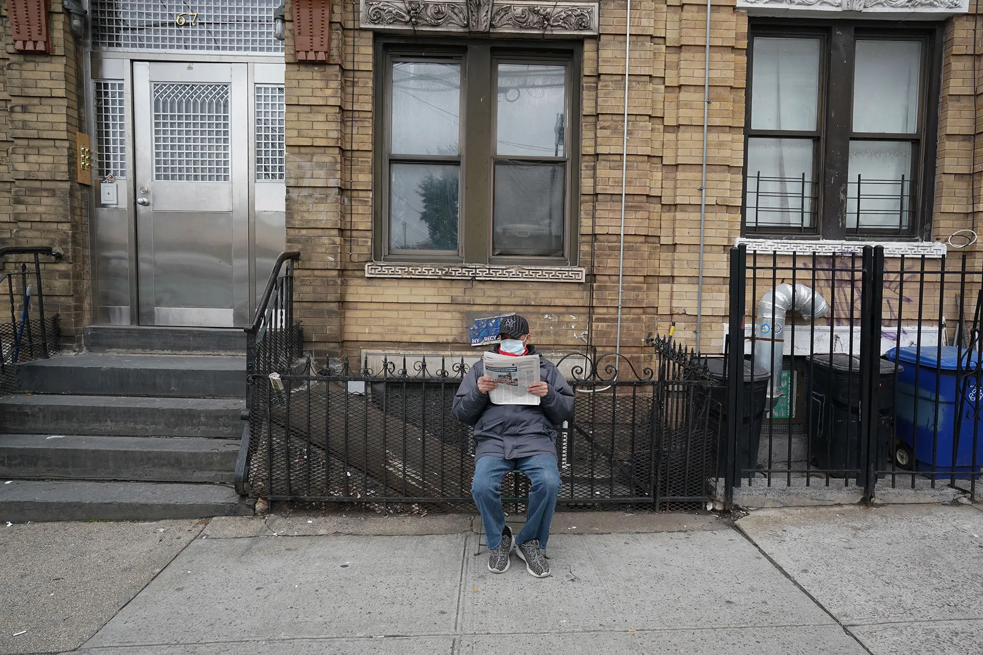 A man reads a&nbsp;newspaper on the sidewalk in&nbsp;Brooklyn, New York, on March 31.