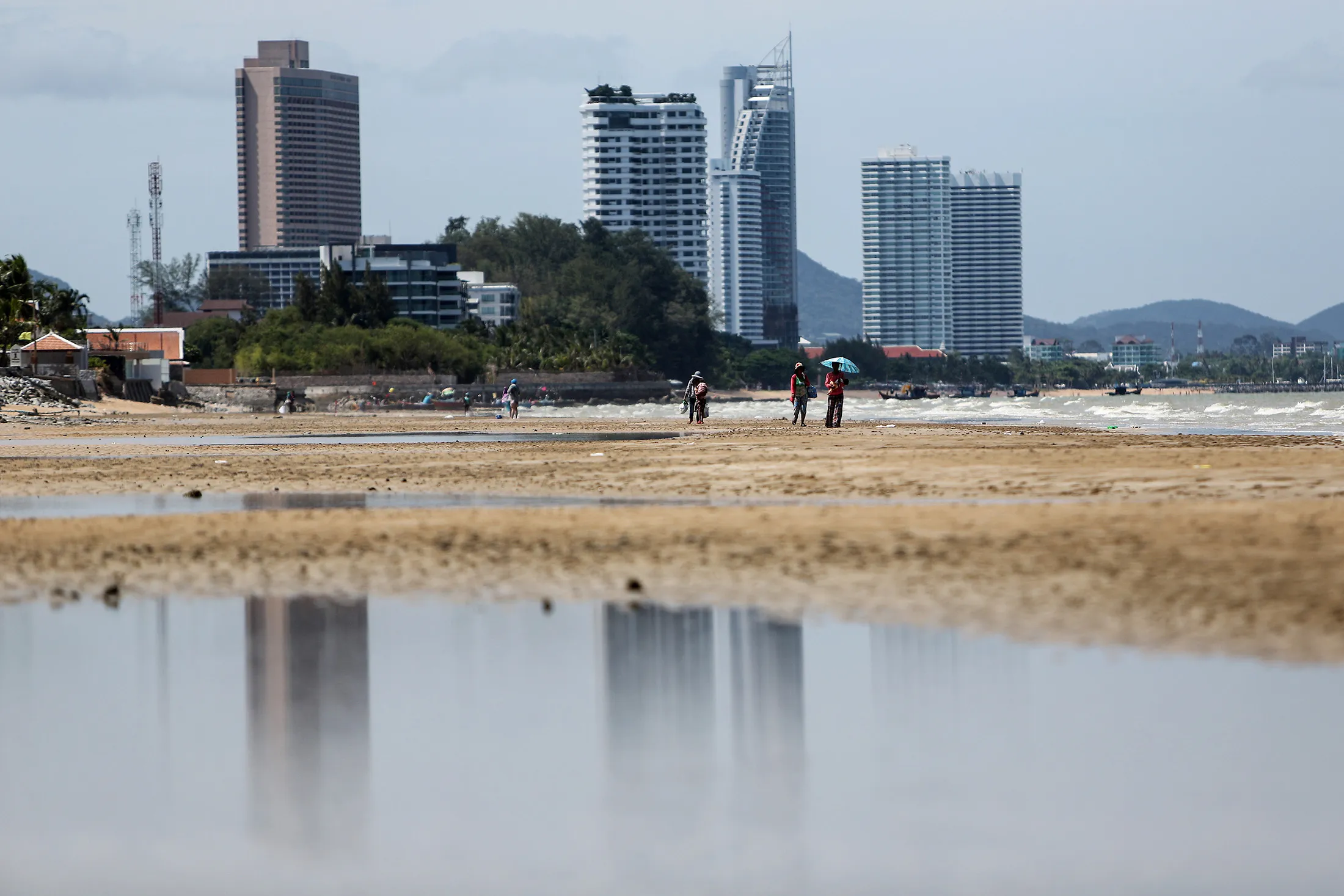 People walk beside the sea on the Jomtien Beach area of Pattaya, Chonburi province, Thailand.
