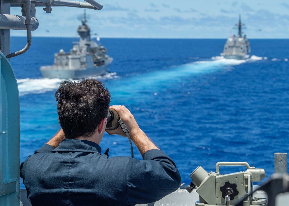 A U.S. sailor views a Royal Australian Navy vessel and a Japan Maritime Self-Defense Force vessel in the South China Sea on July 21.