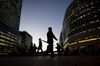 Commuters walk past the JP Morgan, left, and Thomson Reuters Corp., right.