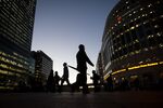 Commuters walk past the JP Morgan, left, and Thomson Reuters Corp., right.