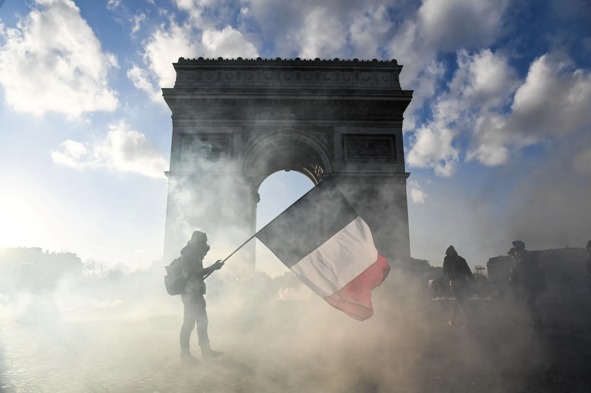 A protester walks among tear gas smoke past the Arc de Triomphe in Paris on March 16.