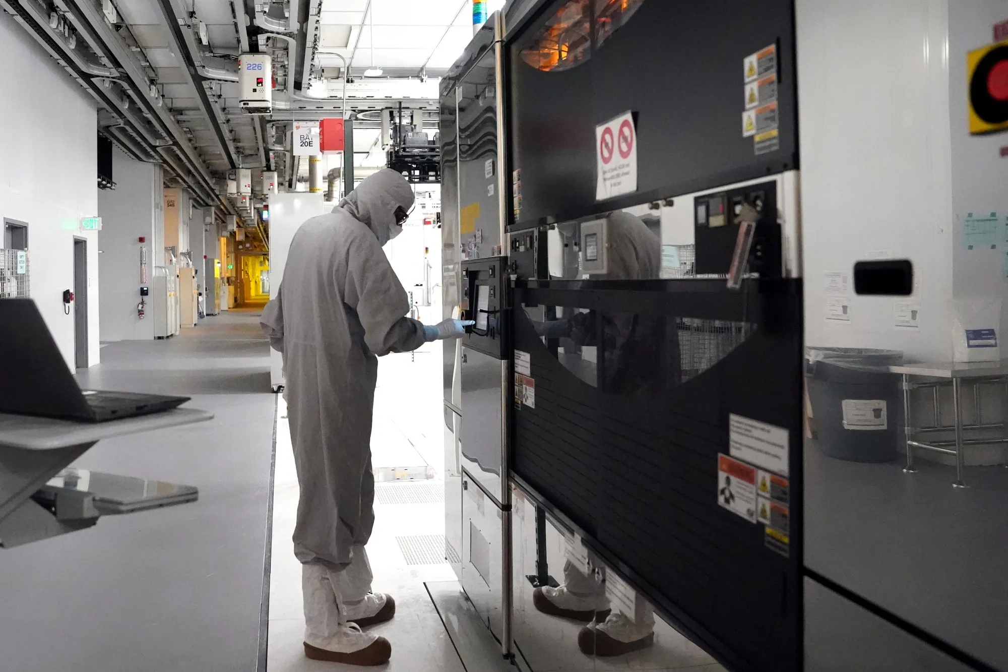 An employee wearing a cleanroom suit performs maintenance inside a semiconductor manufacturing facility in Malta, New York.