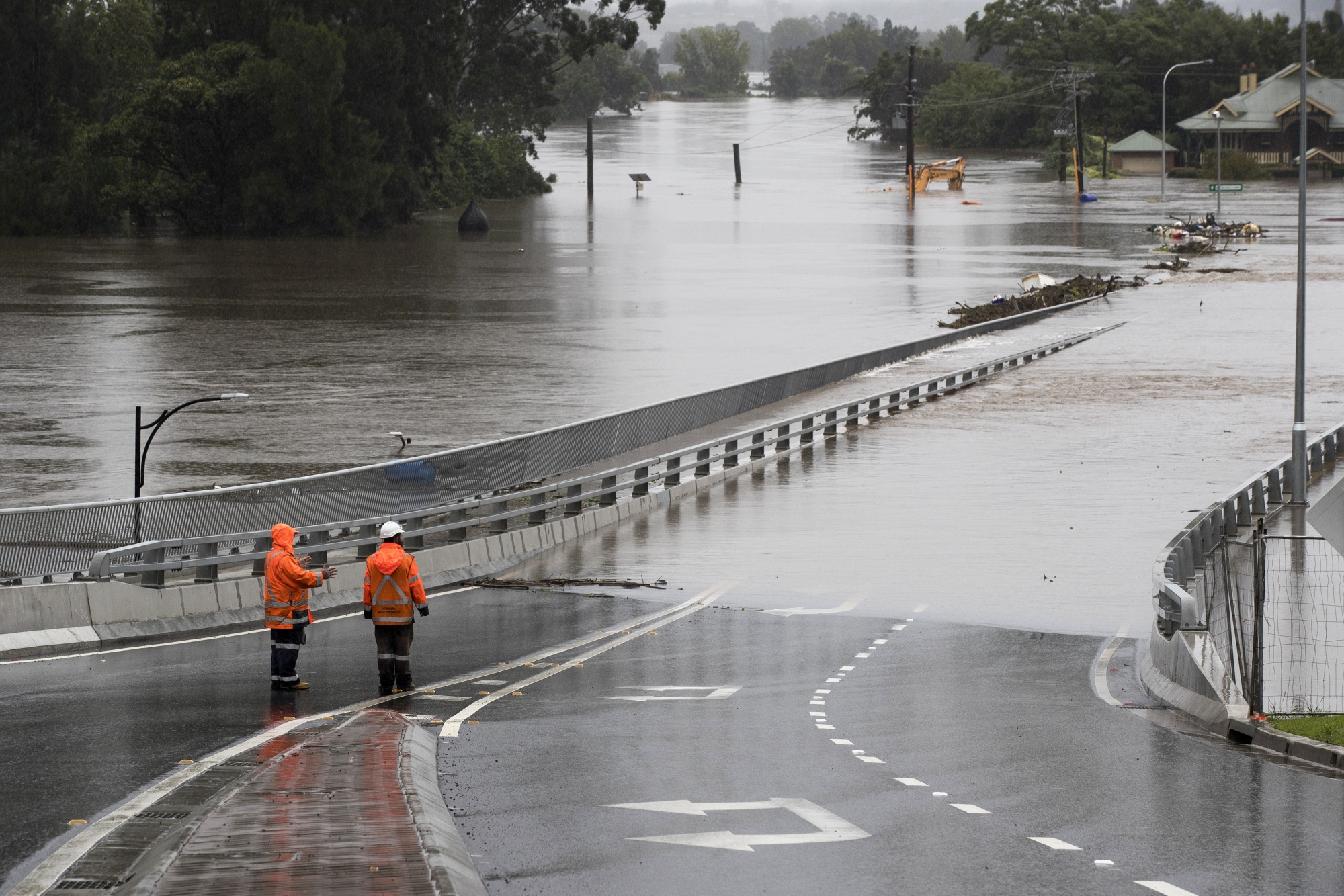 Traffic controllers stand at the Hawkesbury River Bridge submerged by floodwaters in Windsor, New South Wales, earlier in March. 