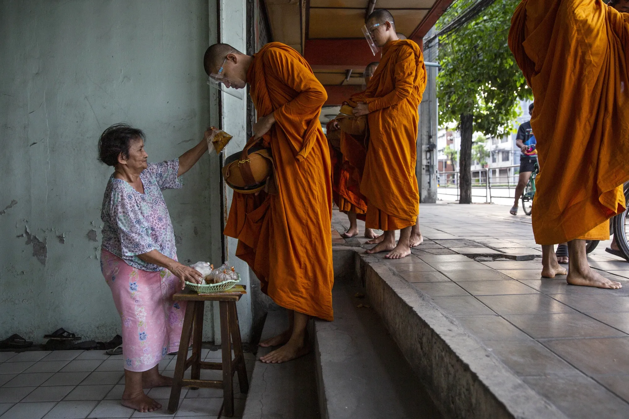 Buddhist monks wearing face shields collect alms during a partial lockdown in Bangkok.