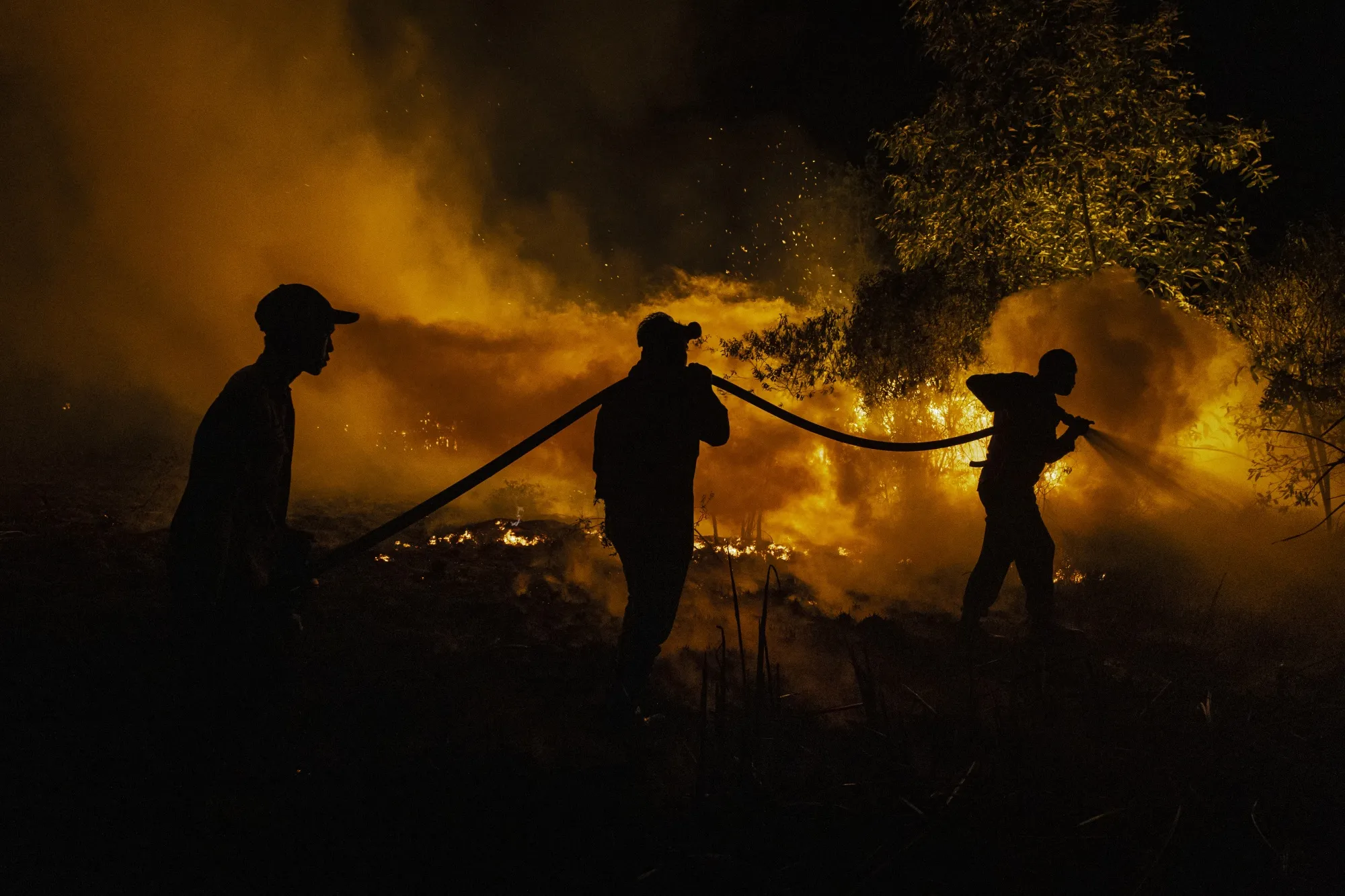 Firefighters attempt to extinguish a wildfire on peatland and fields on Sept. 23 in South Sumatra, Indonesia.&nbsp;