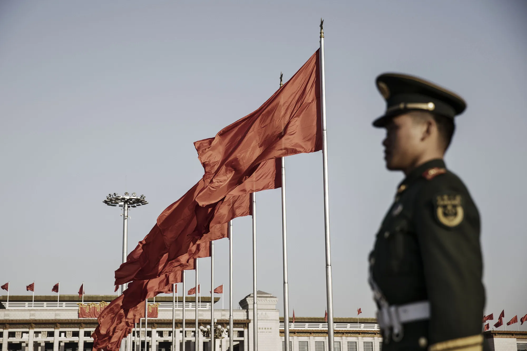 A member of the Chinese People's Armed Police stands guard near red flags at Tiananmen Square in Beijing.