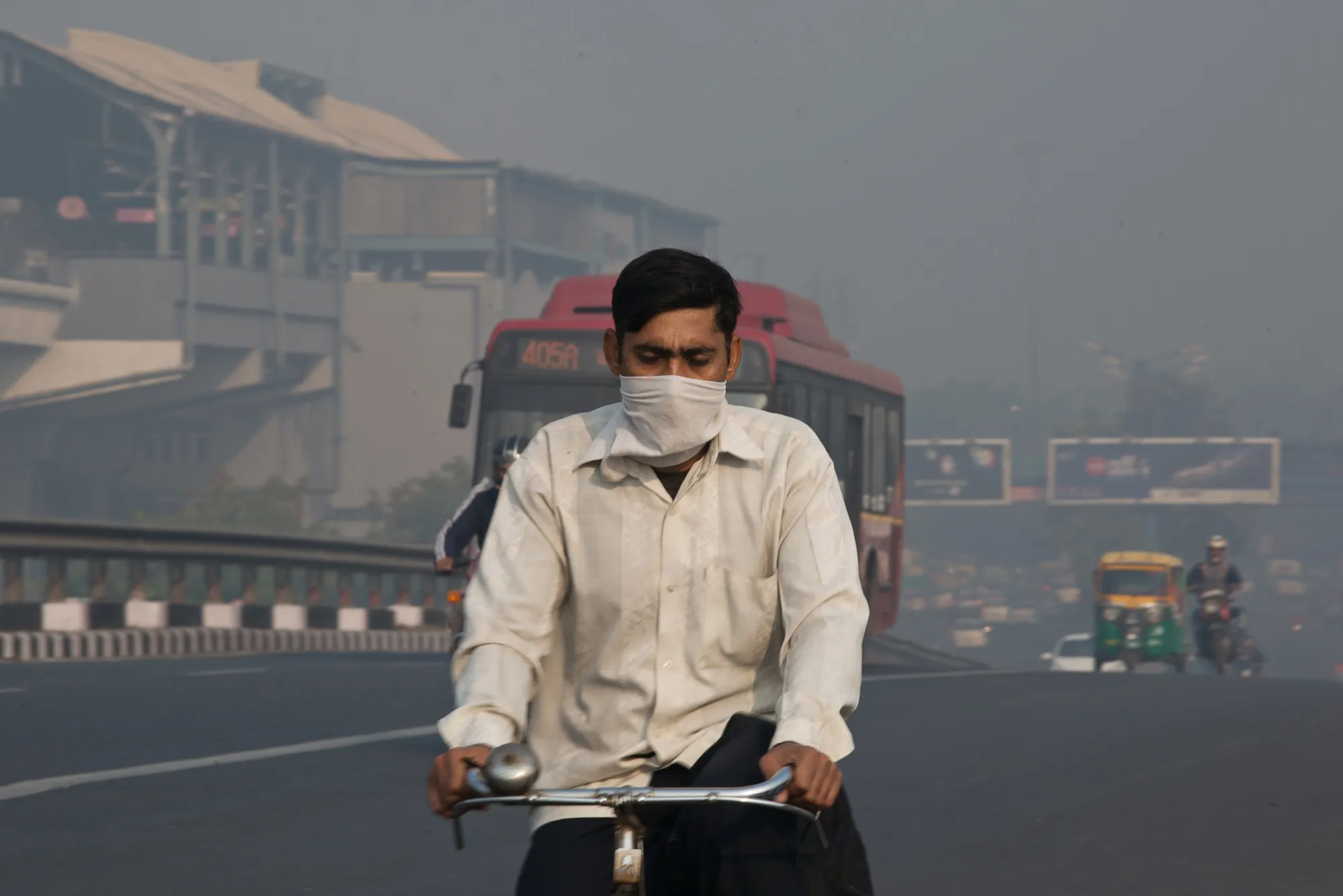 A man wearing a face mask cycles along a road in Delhi.