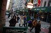 Pedestrians walk along Broadway near the New York Stock Exchange.