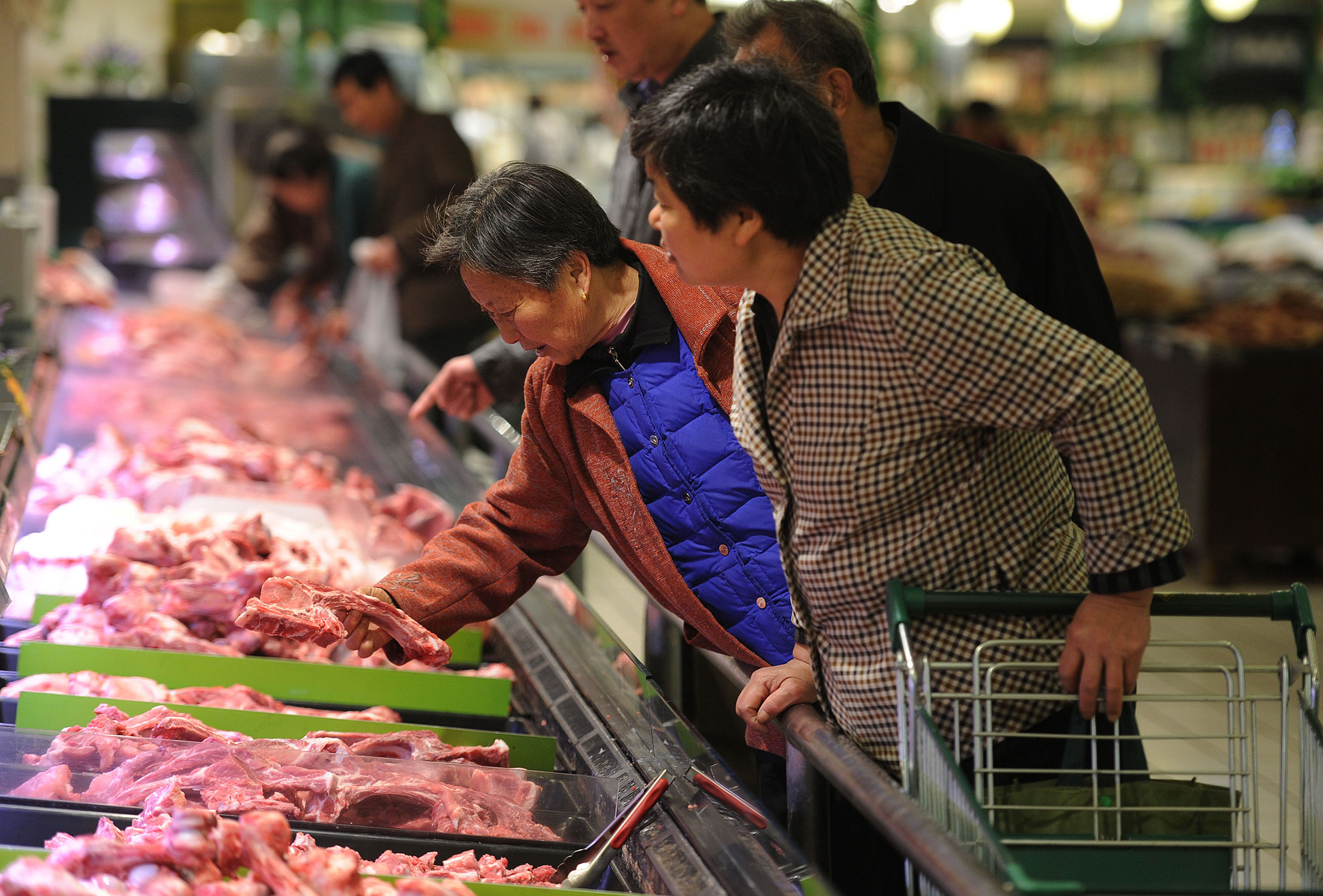 Chinese shoppers select pork at a supermarket in Hefei, east China's Anhui province.
