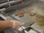 A chef fries hamburgers on a griddle.&nbsp;