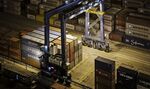 A gantry crane stands next to shipping containers stacked at the Xiamen Songyu Container Terminal at night in Xiamen, China.