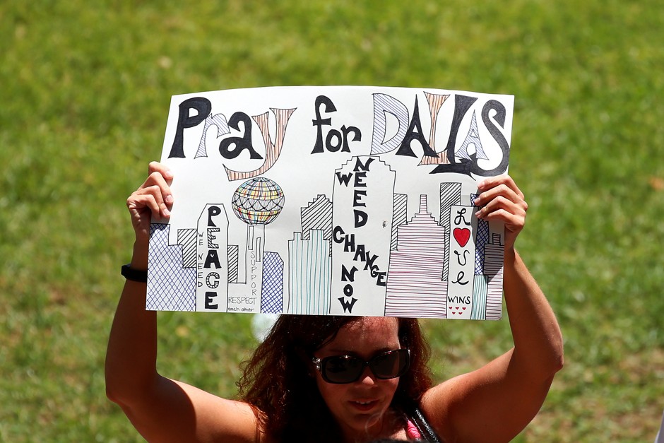 A woman holds up a sign of support during a prayer vigil in a park following the shooting of multiple police officers in Dallas, Texas.