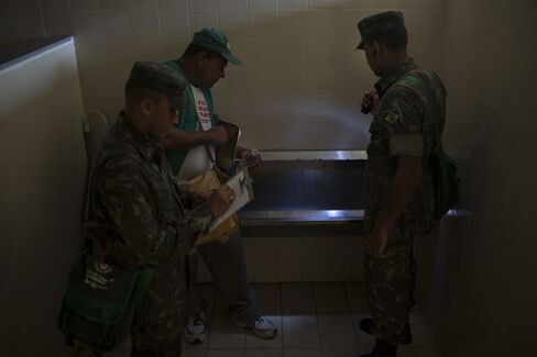 A municipal employee working on a Dengue and Zika prevention campaign and two soldiers from the Brazilian army, inspect a bathroom for signs of mosquitoes in Olinda, Brazil.