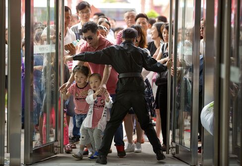 A security guard opens the entrance doors for the grand opening of the Wanda Mall at the Wanda Cultural Tourism City on Saturday.