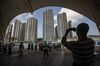 A man uses a smartphone to take a photograph as water front properties stand in the background in Zhuhai, China, on Monday, Oct. 22, 2018. The $15 billion, 55-kilometer (34-mile) bridge, which Xinhua News Agency says is the world’s longest sea link, opens for business on Wednesday.