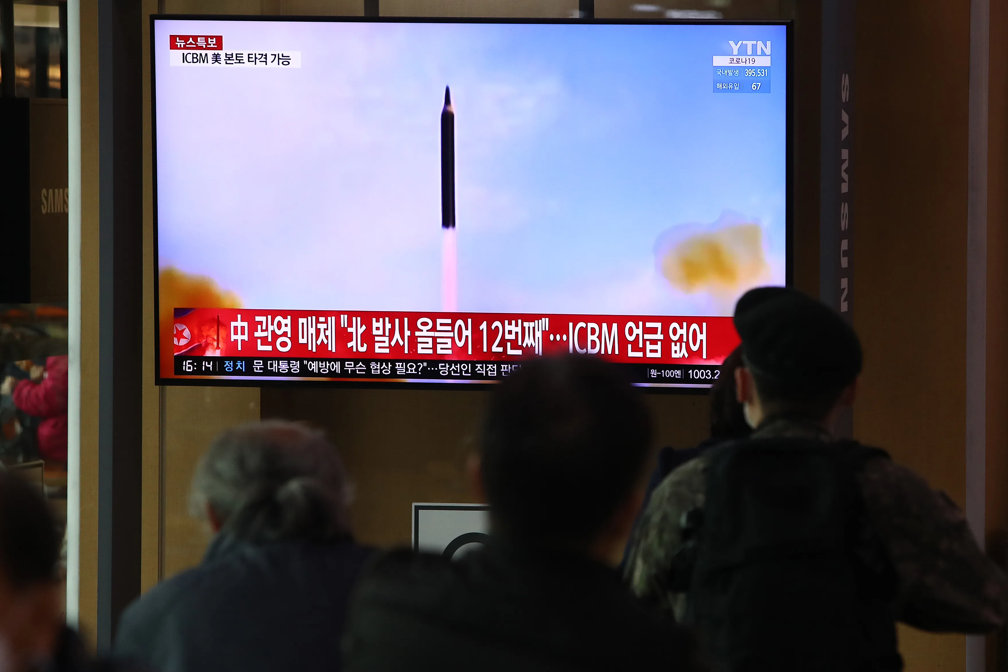 People watch a TV showing a file image of a North Korean missile launch, on March 24.