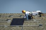 A contractor installs a solar panel on the roof of a new home in Sacramento, California.