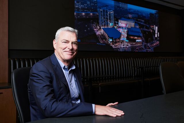 A portrait of Tony Ressler with a rendering of Centennial Yards in the background. 