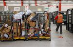 An employee passes trolleys with parcels in Chelmsford, U.K.