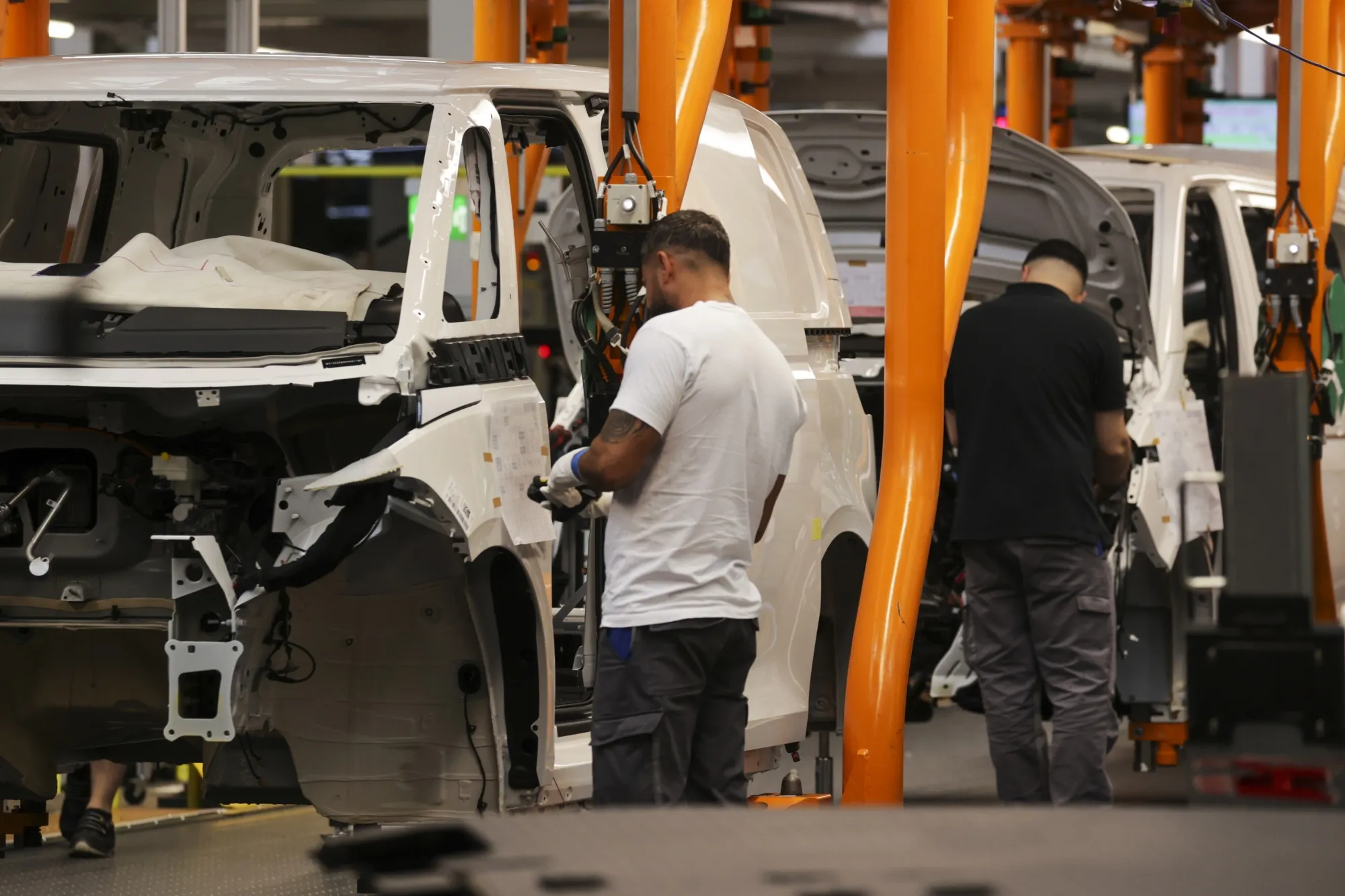 Employees fit components to the body of a Volkswagen ID Buzz electric cargo van on the assembly line at the Volkswagen AG&nbsp;plant in Hannover, Germany.