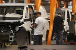 Employees fit components to the body of a Volkswagen ID Buzz electric cargo van on the assembly line at the Volkswagen AG plant in Hannover, Germany.