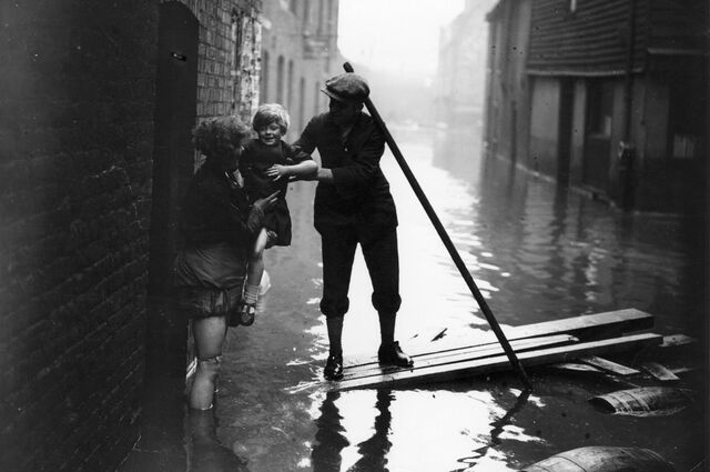 A man rescuing a mother and child during flooding in Rotherhithe, south London, caused by the Thames bursting its banks in 1928.