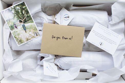 An opened Pour This box that includes wine bottles, thank you note, and promotional material.