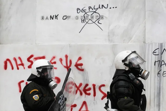 Riot police pass outside the main building of the Bank of Greece during clashes in Athens