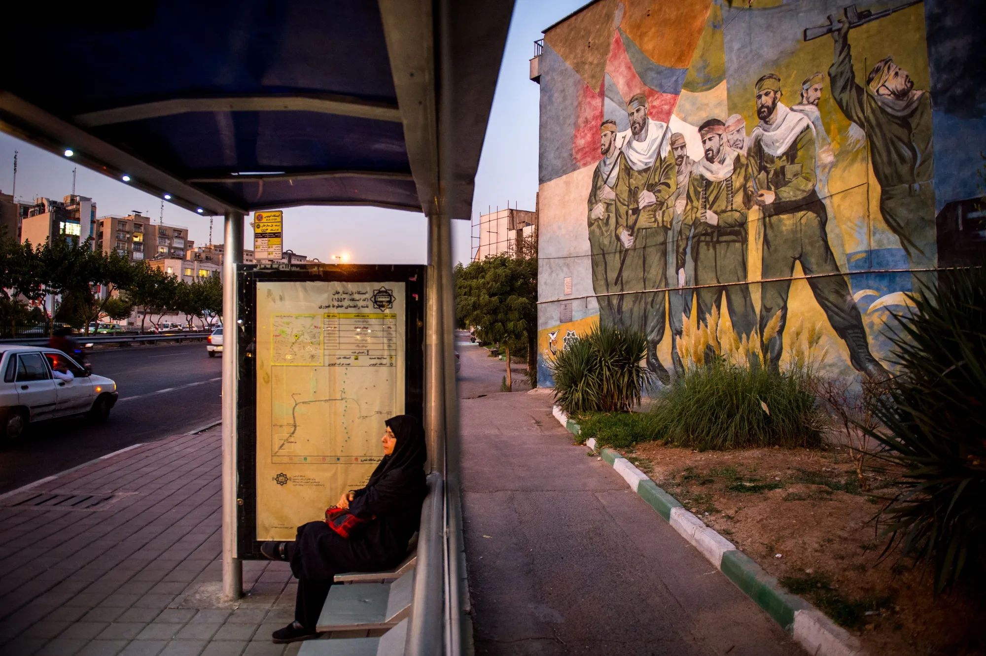 A woman waits at a bus stop&nbsp;in Tehran.