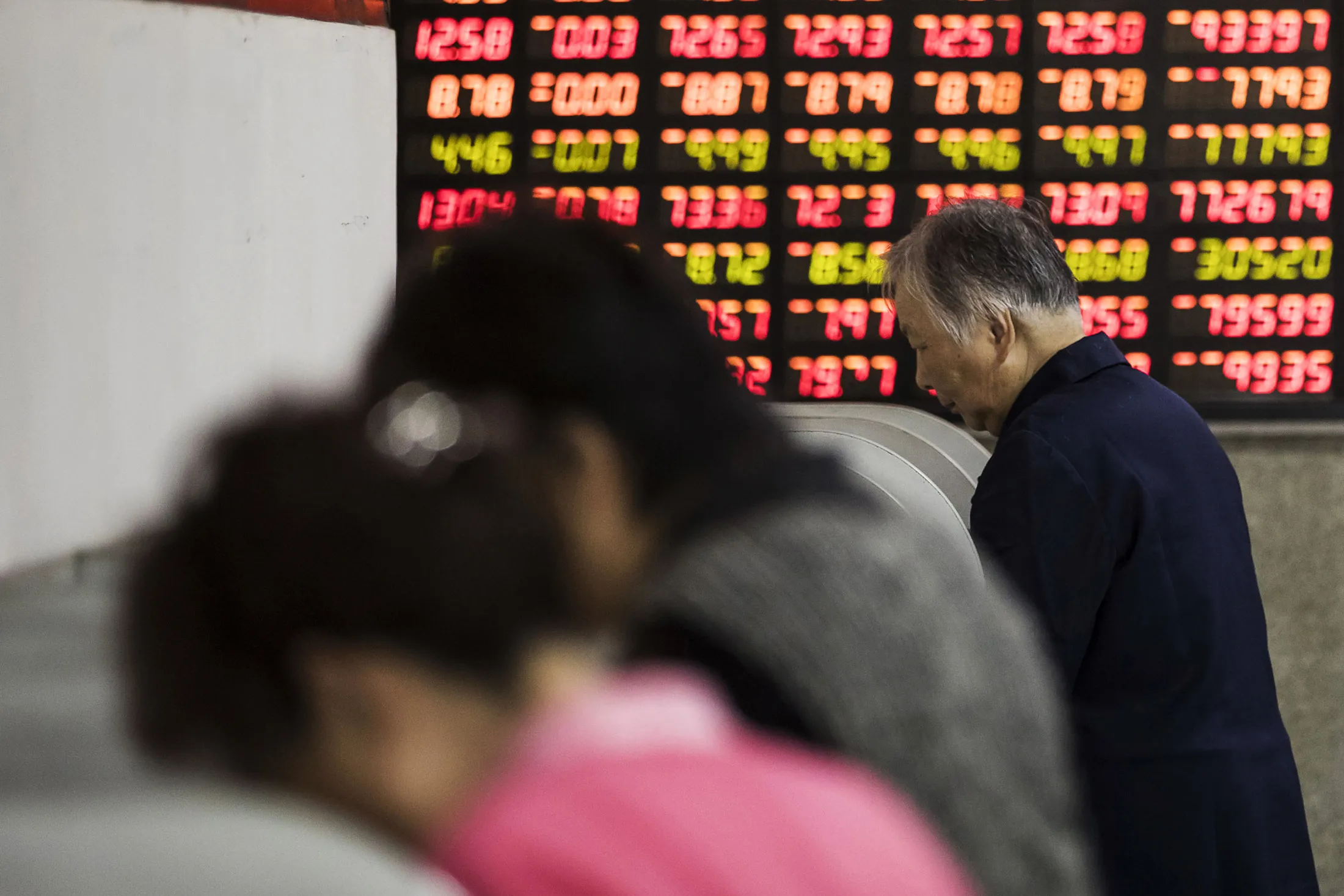 Investors stand at trading terminals in front of electronic stock boards at a securities brokerage in Shanghai, China, on&nbsp;Oct. 13.