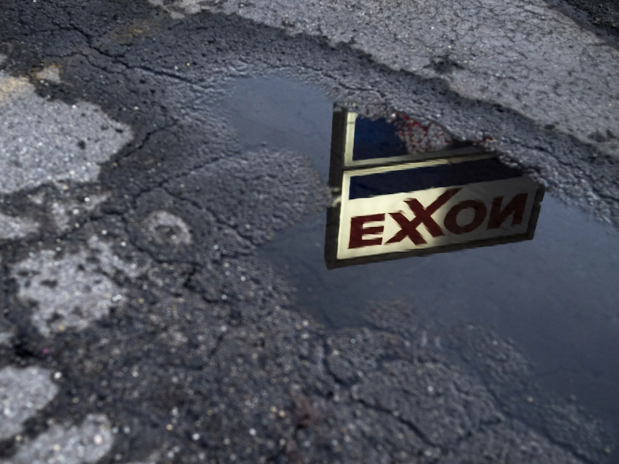 Exxon Mobil Corp. signage is reflected in a puddle at a gas station in Nashport, Ohio.