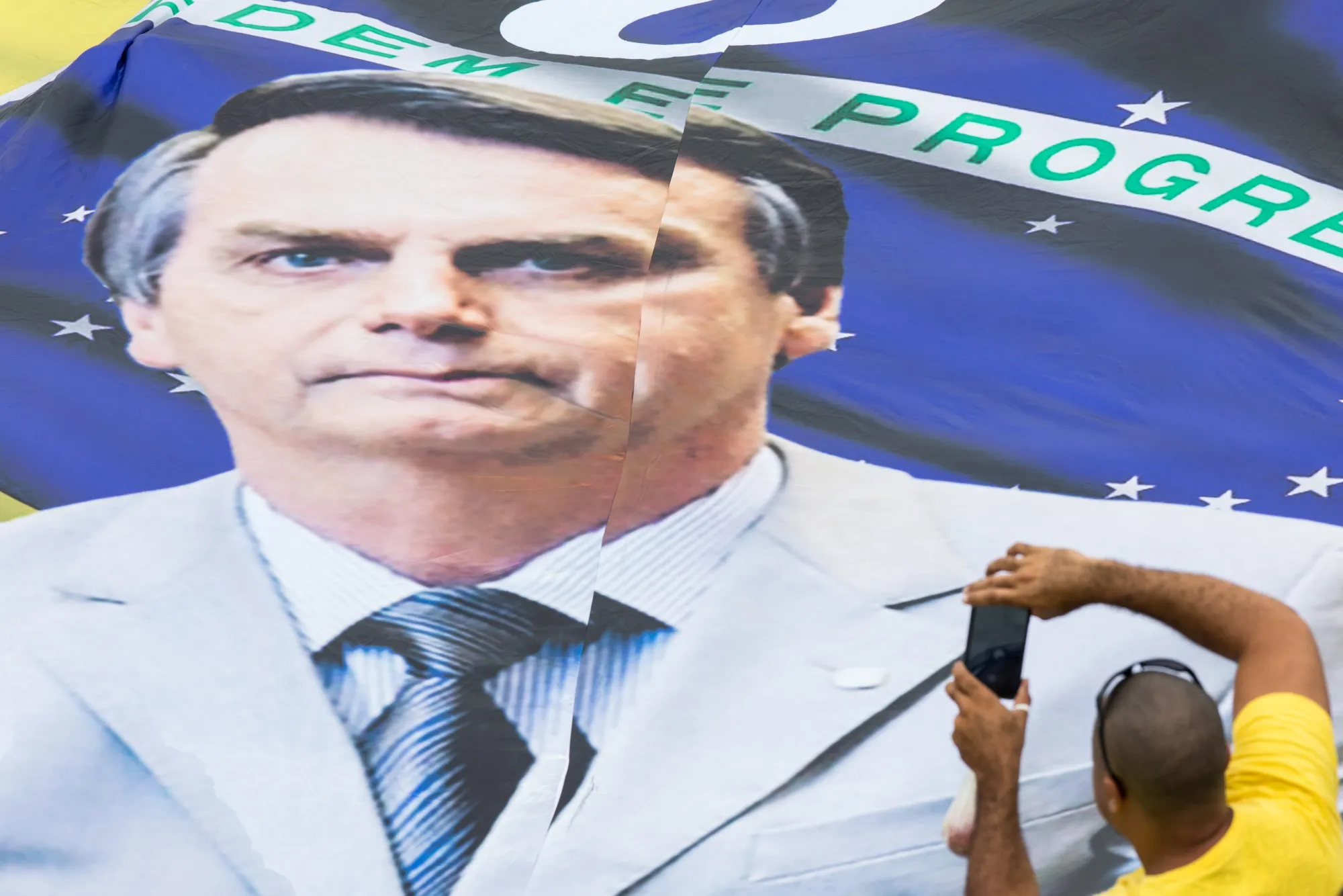 A supporter&nbsp;takes a photograph of a banner during the 38th presidential inauguration of Jair Bolsonaro in 2019.
