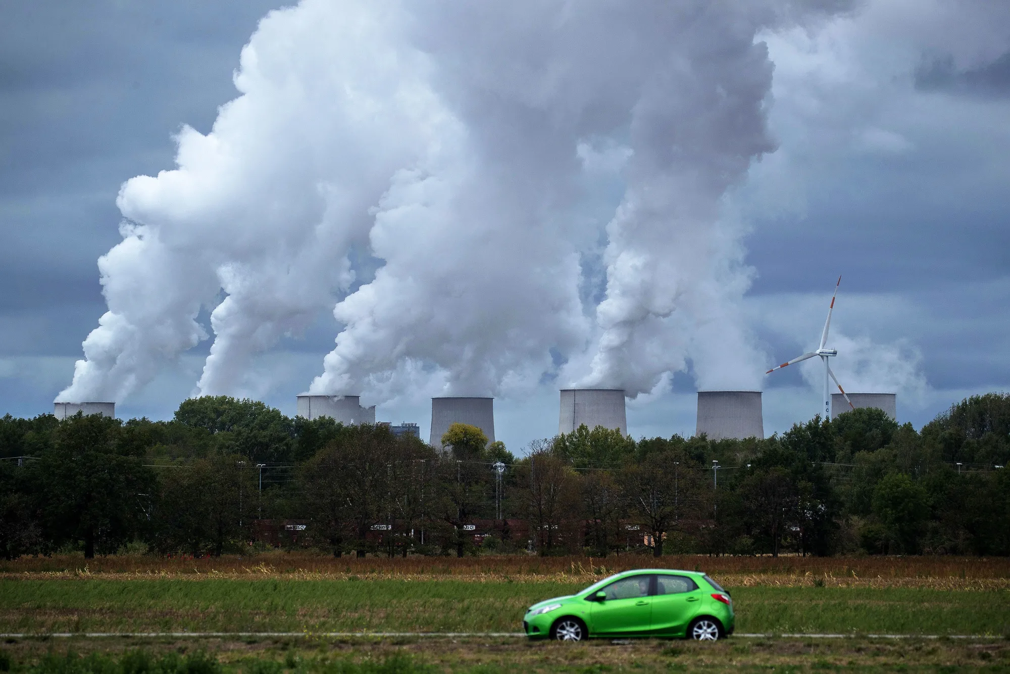 A wind turbine operates near emissions rising from the Jaenschwalde lignite fired power plant in Barenbrueck.