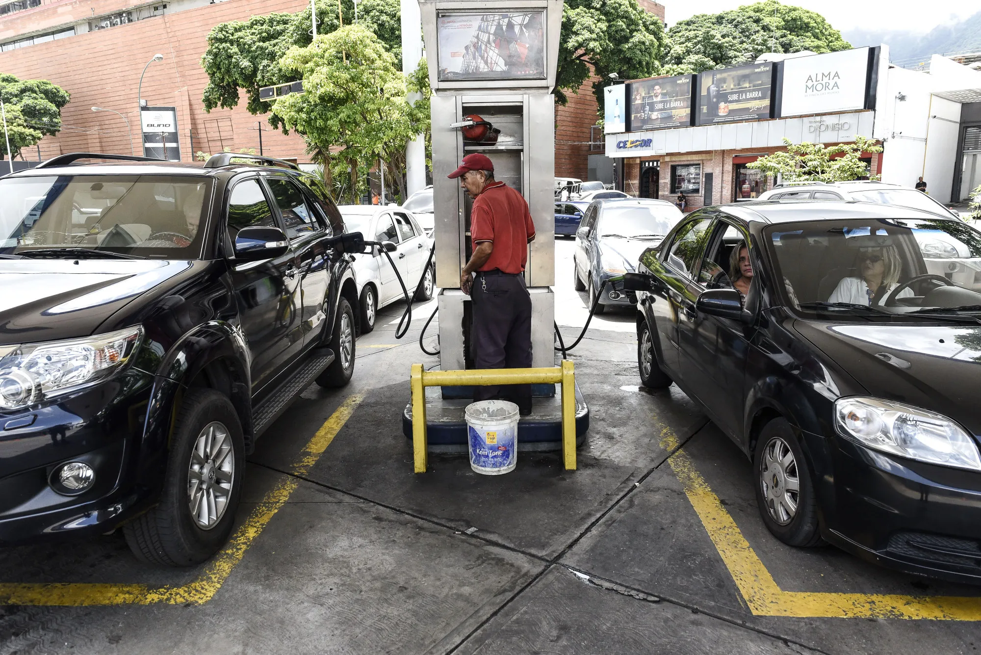 An employee fuels vehicles at a&nbsp;gas station in Caracas.