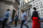 Pedestrians walk along Wall Street near the New York Stock Exchange (NYSE) in New York, U.S..