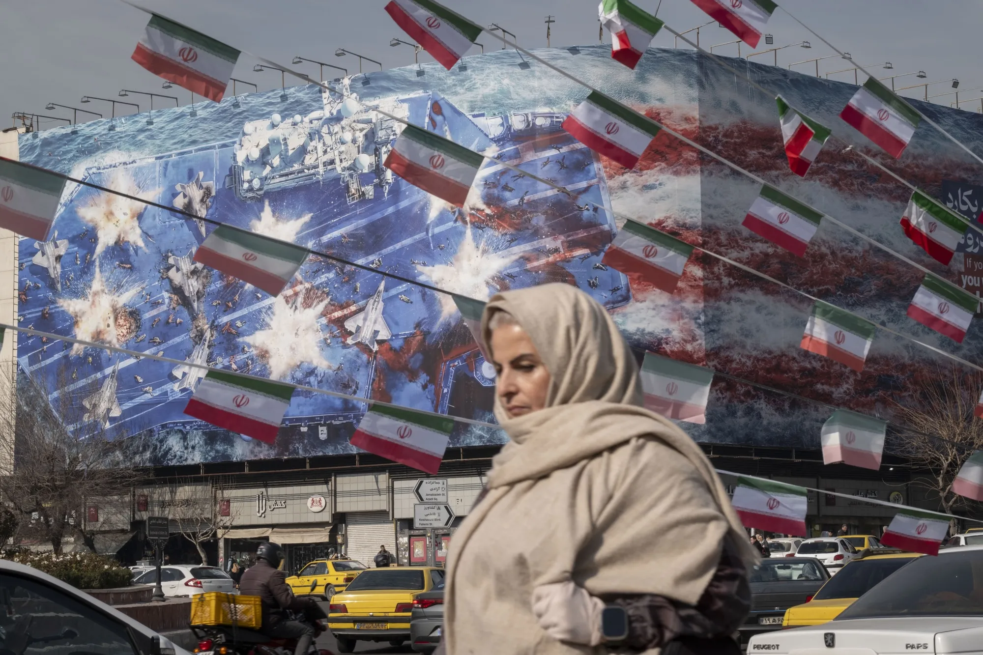 A woman passes a building showing an anti-US billboard, in Tehran.