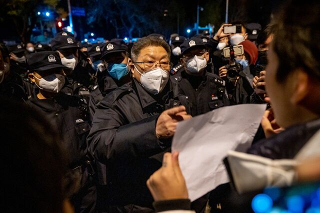 A local official speaks with a demonstrator holding a blank sign during a protest in Beijing in November 2022. 