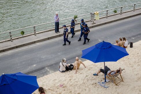 Police patrol along the Seine as people relax on artificial beaches in Paris.