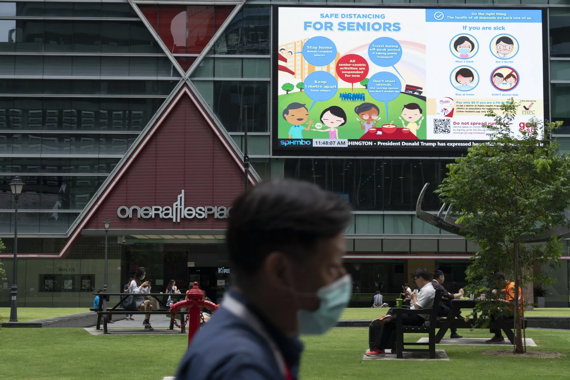 A pedestrian passes a billboard displaying information on "Safe Distancing For Seniors" at Raffles Place in Singapore.
