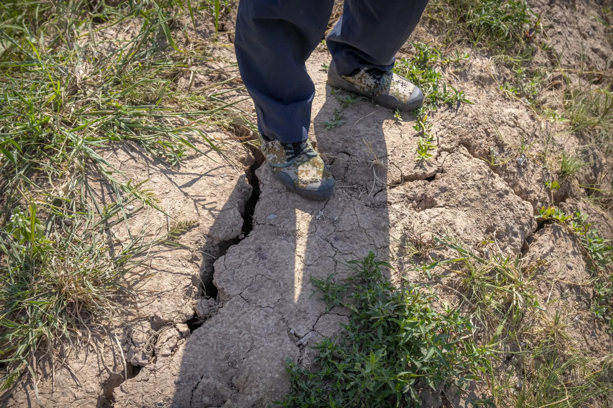 A farmer stands above a deep crack in the dried mud of an earthen embankment in his rice fields on the outskirts of Chongqing, China,&nbsp;Aug. 21.