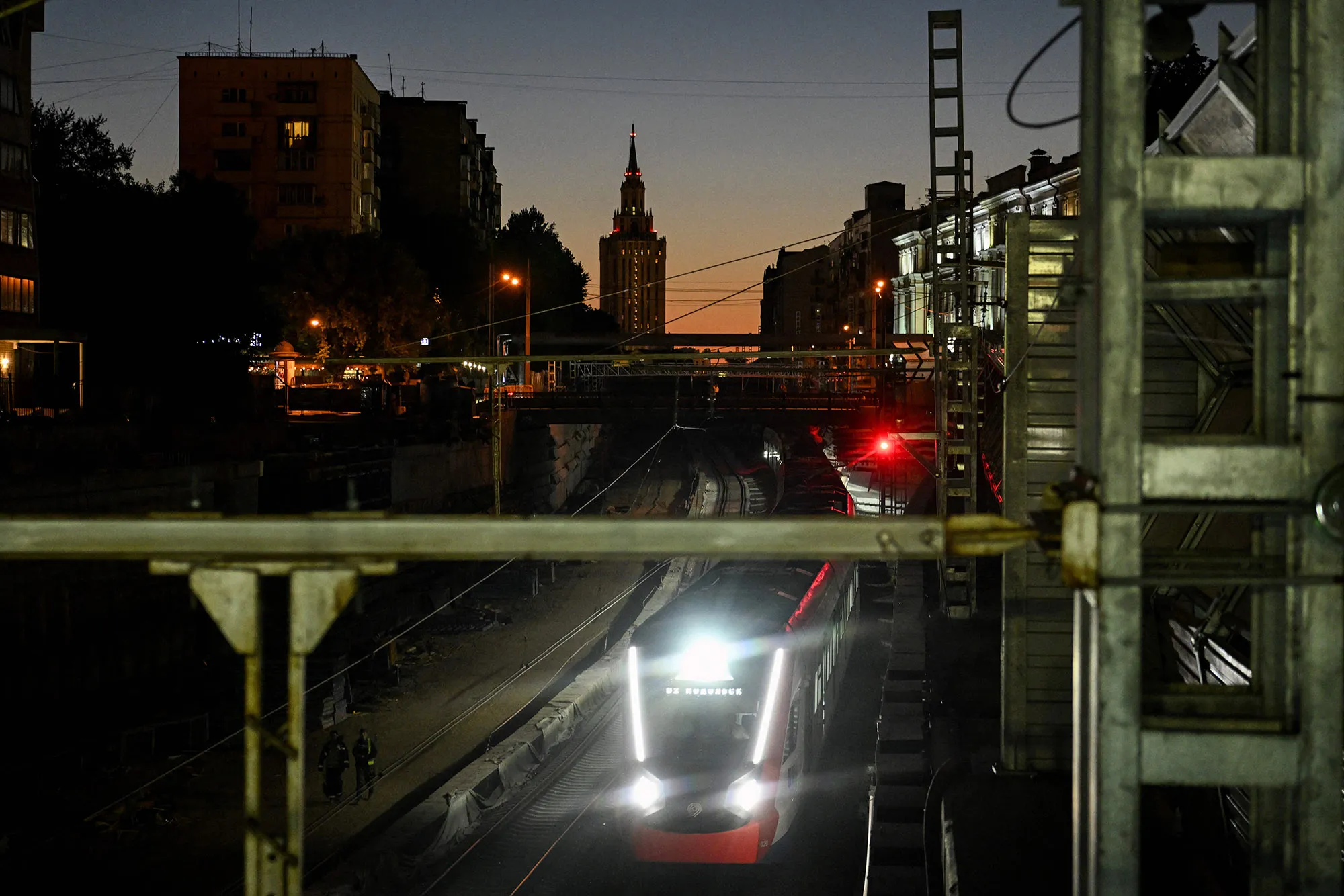 A&nbsp;train rides under a bridge with a Stalin-era skyscraper&nbsp;in Moscow.