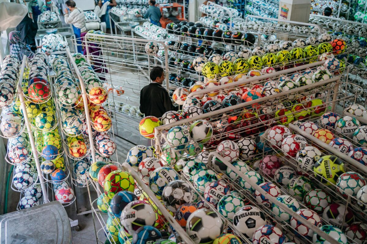 Workers collect and examine completed balls at a factory