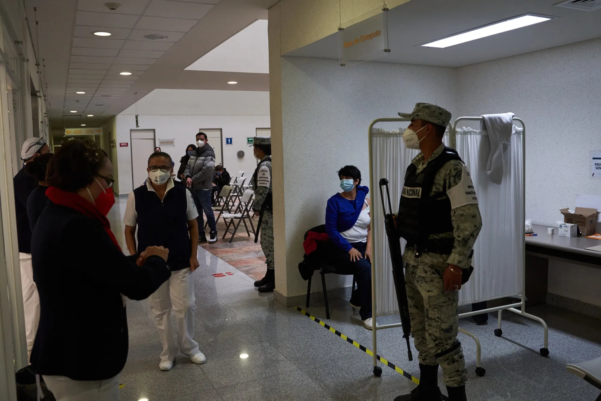 A member of the National Guard stands near healthcare workers administering doses of the Pfizer BioNtech Covid-19 vaccine at the Centenario Hospital Miguel Hidalgo in Aguascalientes, Mexico, on&nbsp;Jan. 14.