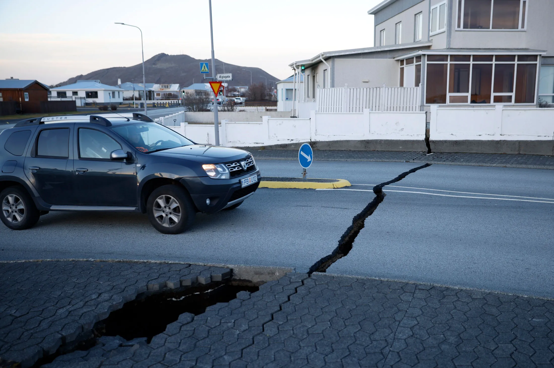 A car drives toward a fissure in a road in Grindavik, Iceland, on Nov. 13.